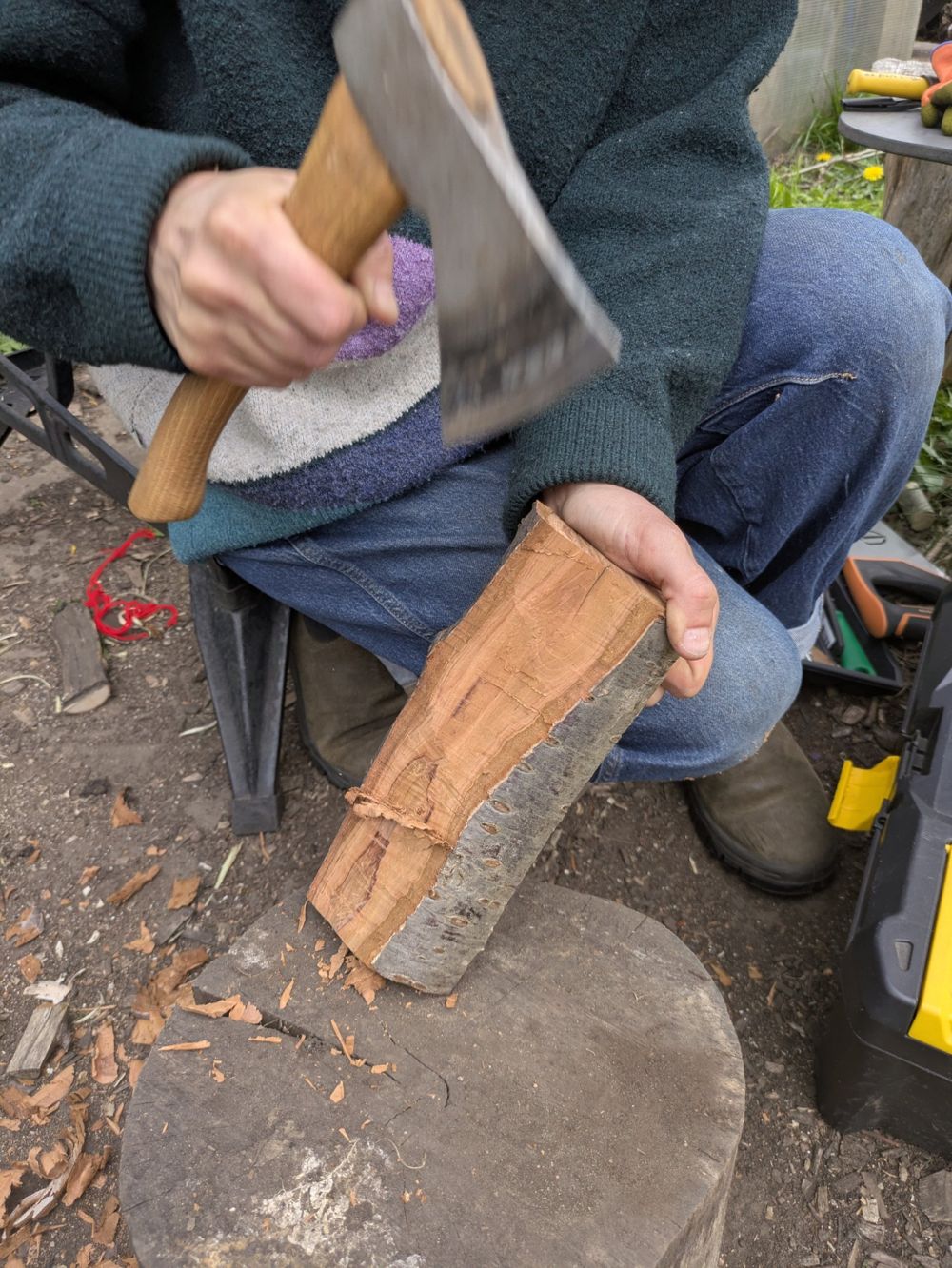 Close-up of hands shaping a log with an axe
