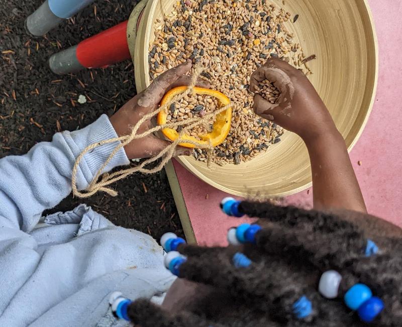Children making a bird feeder with seeds and string