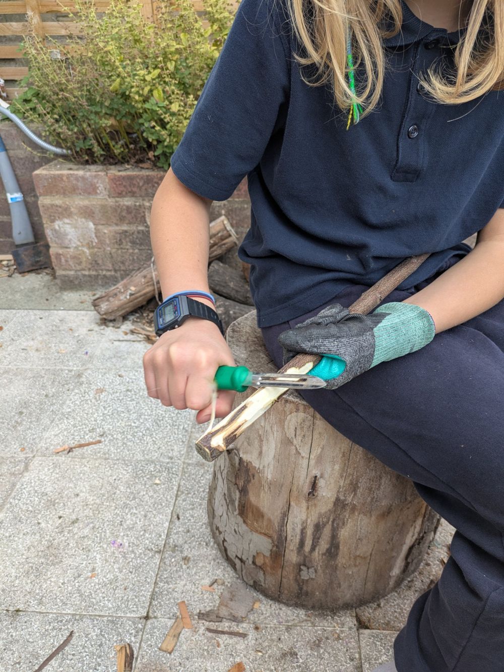 A child whittling a stick with a peeler