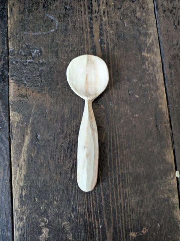 A pale wooden eating spoon on an old table