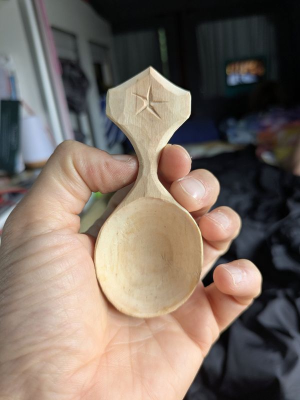 A small wooden scoop with a carved star on the handle
