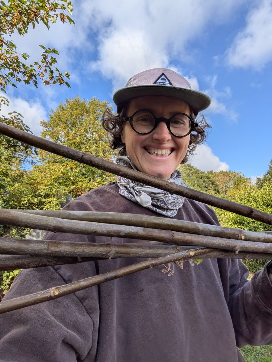Holly smiling under autumn trees, holding an armful of freshly cut branches